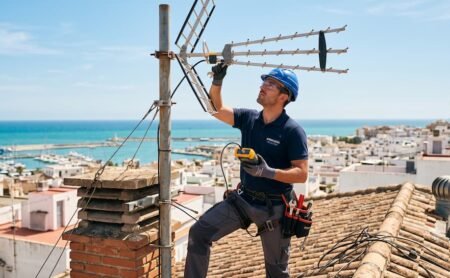 Técnico profesional revisando la instalación de antena de televisión en un tejado de Cádiz.